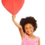 Girl holding up paper heart.