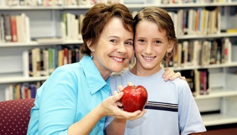 Boy offering an apple to his teacher
