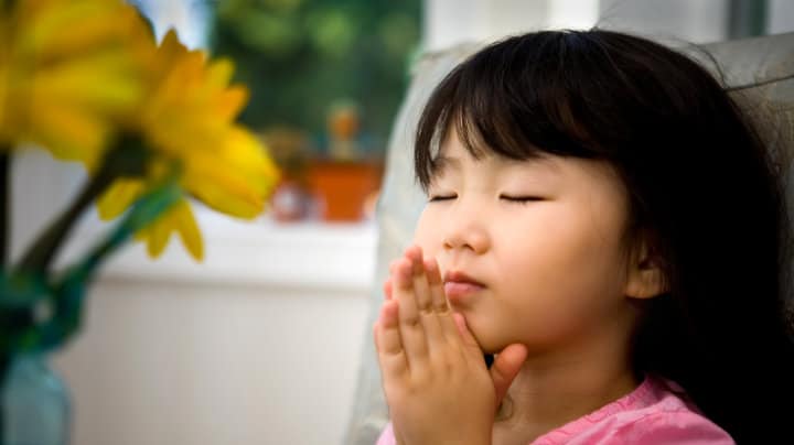 young girl praying with hands raised