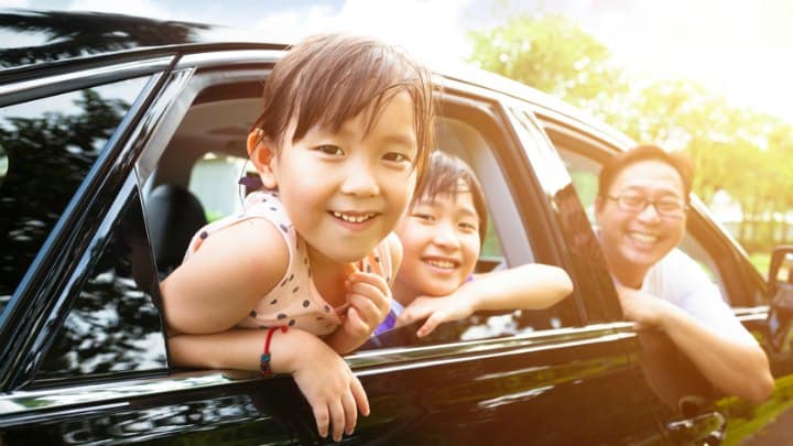 happy little girl with family sitting in the car
